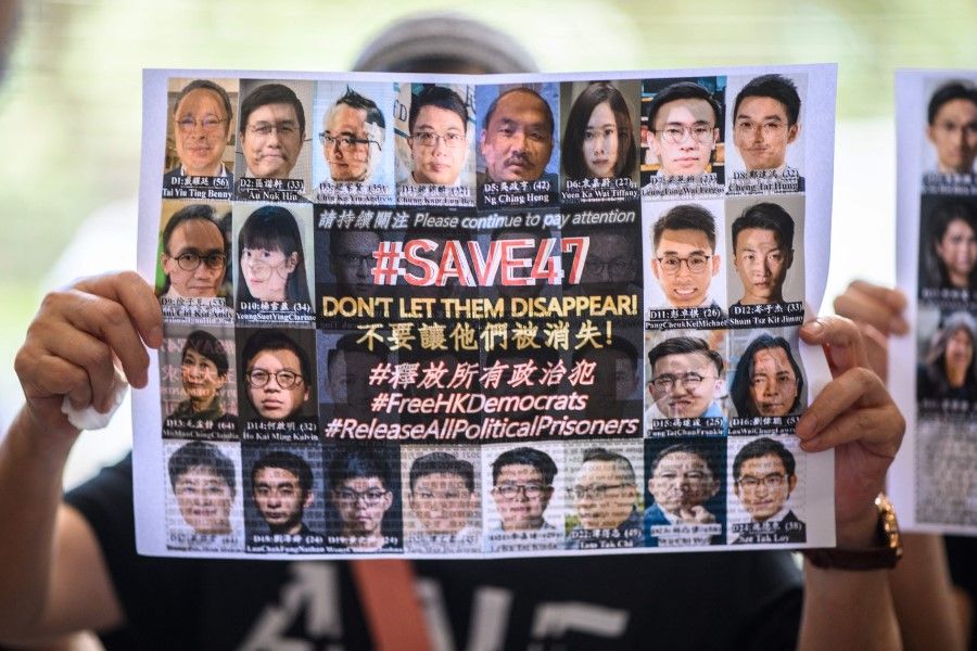 A supporter holds a poster showing some of the 47 pro-democracy activists on trial at the West Kowloon Court in Hong Kong on 8 July 2021, on charges of conspiracy to commit subversion under the national security law for taking part in unauthorised pro-democracy primaries in July 2020. (Anthony Wallace/AFP)