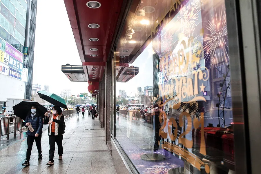 Pedestrians wearing protective masks and holding umbrellas walk past stores in Taipei, Taiwan, 11 January 2021. (I-Hwa Cheng/Bloomberg)