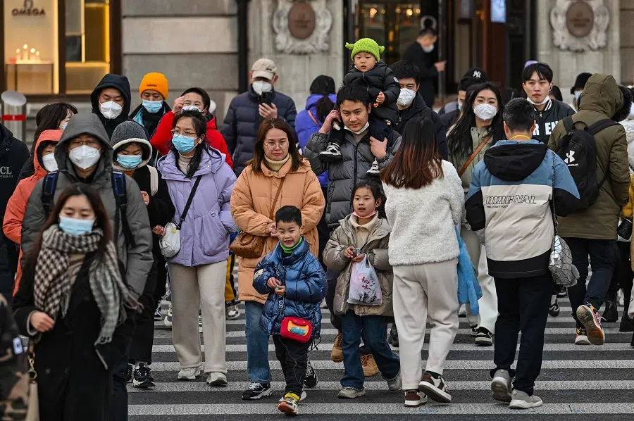 People cross a street on the Bund in the Huangpu district in Shanghai, China, on 16 January 2023. (Hector Retamal/AFP)