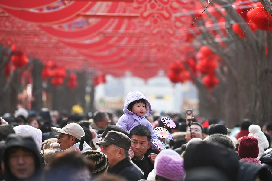 A man carries a child above the crowd at a temple fair in Beijing, China, on 30 January 2025. (Greg Baker/AFP)