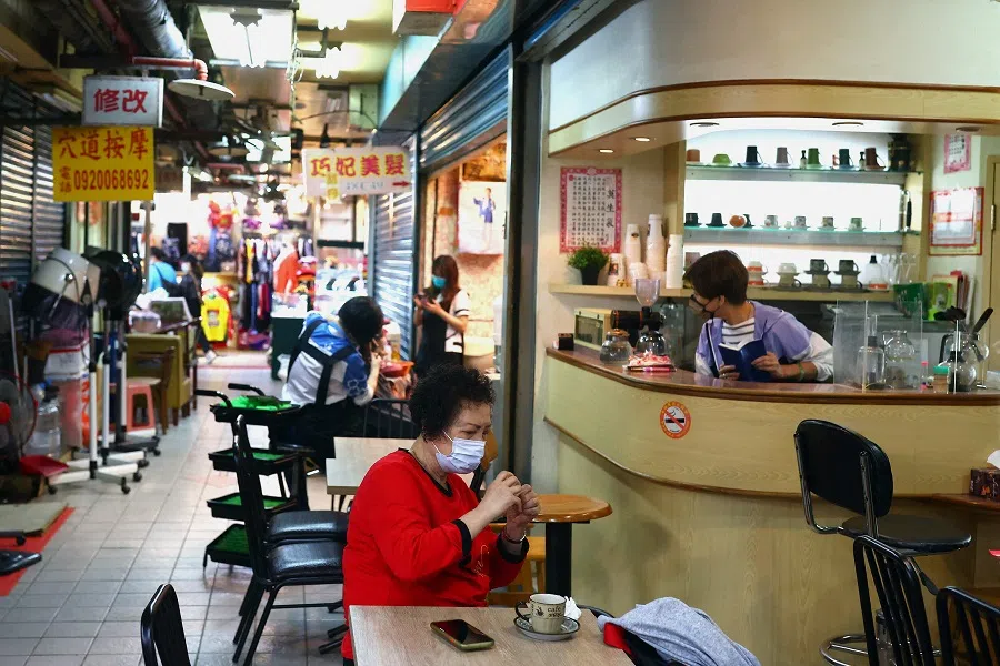 A woman sits at a cafe inside a market in Keelung, Taiwan, 23 May 2022. (Ann Wang/Reuters)