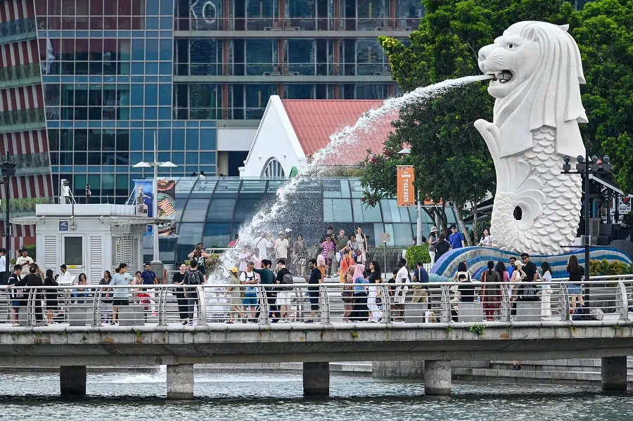 People gather around the Merlion statue at the Marina Bay waterfront in Singapore on 13 May 2024. (Roslan Rahman/AFP)