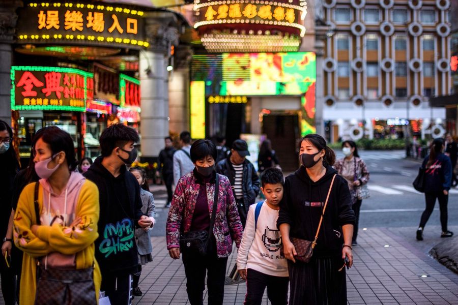 Pedestrians wear face masks as they walk along a pavement in Macau on 22 January 2020, after the former Portuguese colony reported its first case of the new SARS-like virus that originated from Wuhan in China. (Anthony Wallace/AFP)