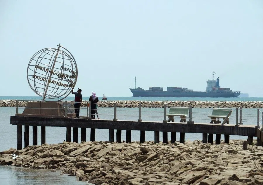 A container ship enters the Singapore Strait for the Strait of Malacca, as tourists stand at mainland Asia's southernmost point in Johor, Malaysia, on 12 November 2016.