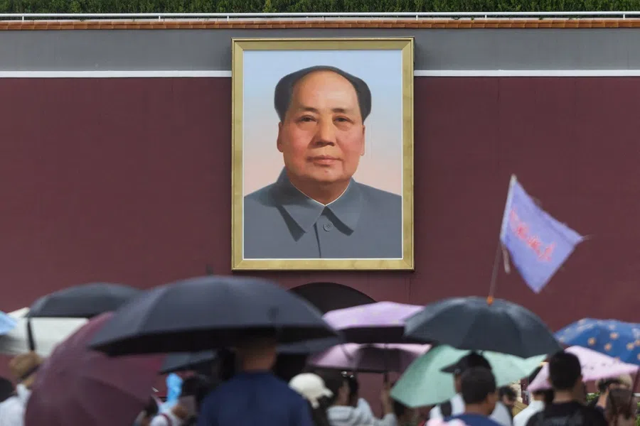 People with umbrellas gather in front of Tiananmen Gate featuring a portrait of late Chinese leader Mao Zedong, in Beijing, China, on 12 August 2026.