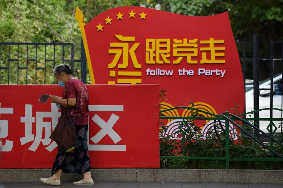 A woman walks past a Communist Party slogan urging people to "Follow the Party forever" outside a residential compound in Beijing on 6 July 2020. (Greg Baker/AFP)