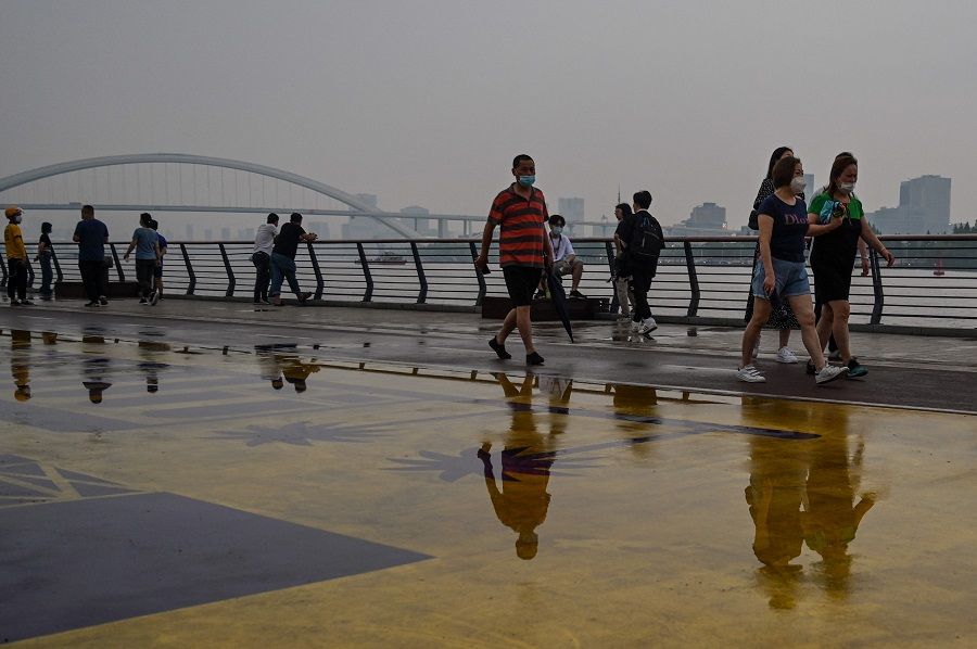 People walk in a park along Huangpu River in Shanghai, China, on 19 June 2022. (Hector Retamal/AFP)