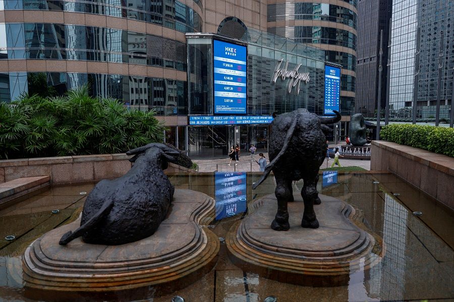Bull statues are placed in font of screens showing the Hang Seng stock index and stock prices outside Exchange Square, in Hong Kong on 18 August 2023. (Tyrone Siu/Reuters)