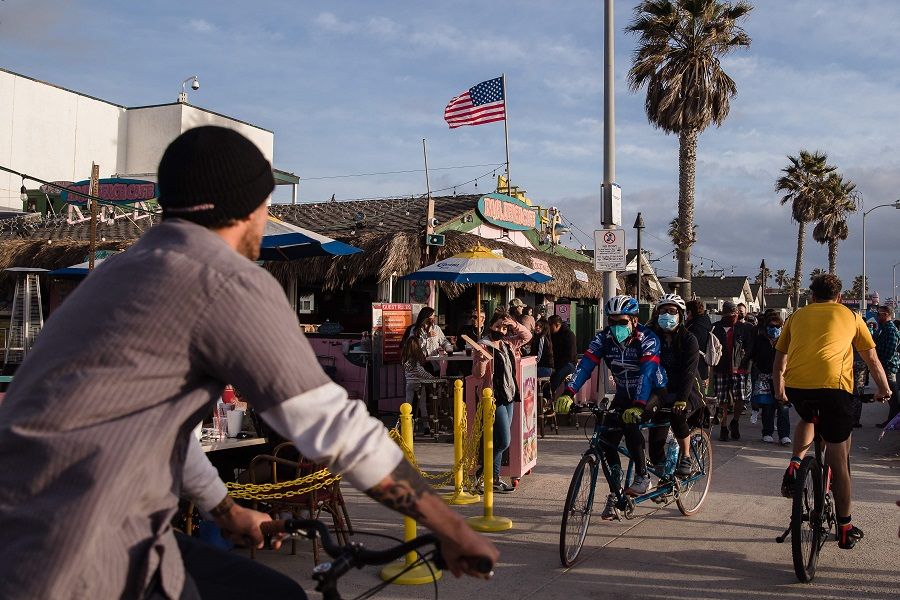 Crowds of people bike and walk the boardwalk in Pacific Beach in San Diego, California, US, on 13 February 2021. (Ariana Drehsler/AFP)