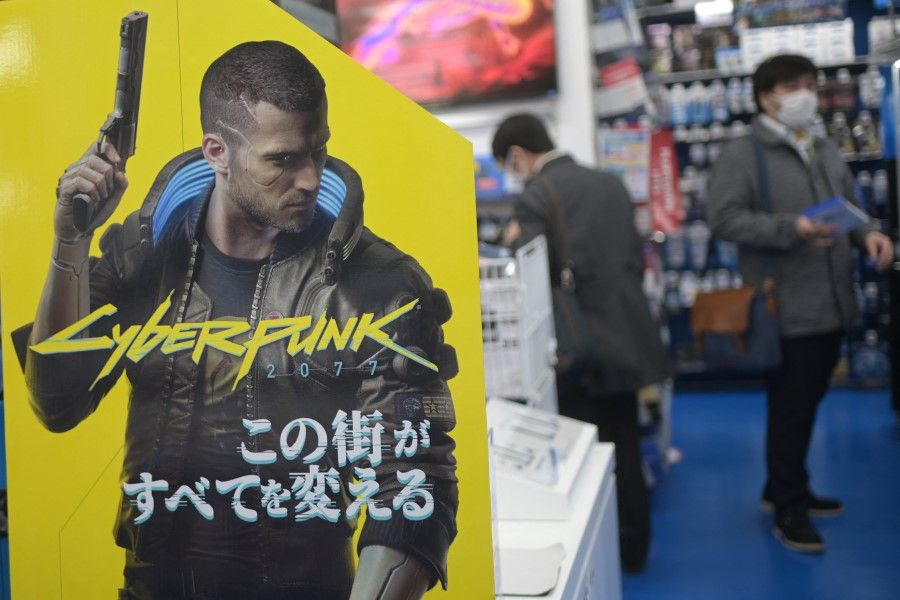 This file photo taken on 18 December 2020 shows an advertisement for the Cyberpunk 2077 video game for the Sony Playstation, as shoppers browse the gaming section of a shop in Tokyo. (Philip Fong/AFP)