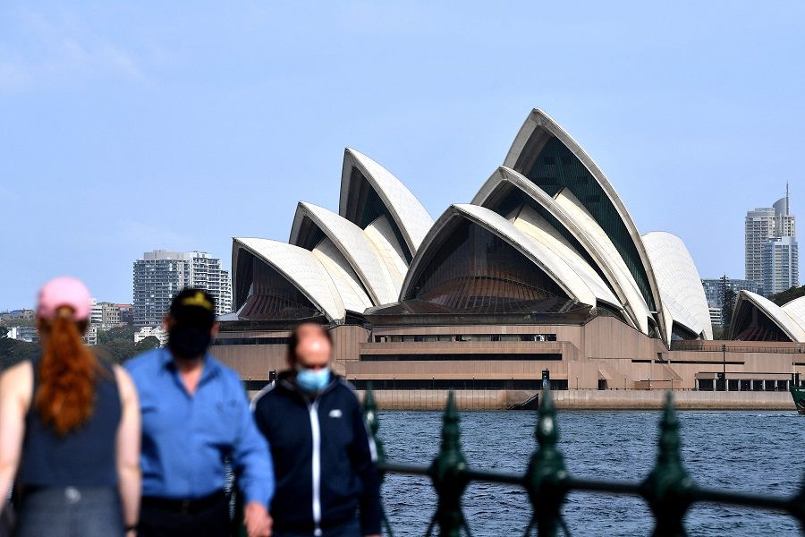 People wearing face masks walk in front of the Opera House in Sydney on 10 September 2021. (Saeed Khan/AFP)