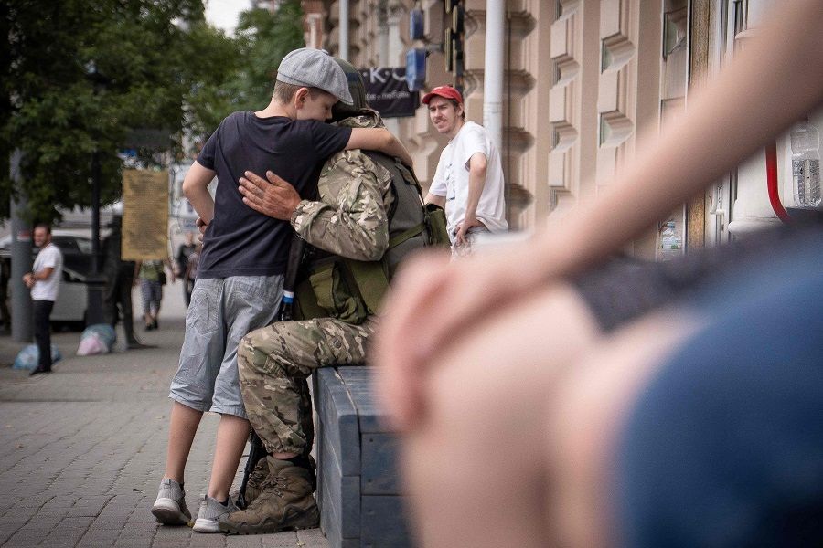 A young boy hugs a member of the Wagner Group in Rostov-on-Don, Russia, on 24 June 2023. (Roman Romokhov/AFP)