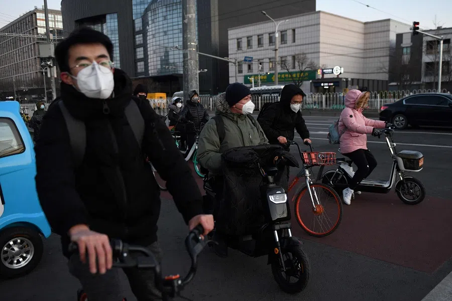 People wear face masks as a preventive measure against the Covid-19 coronavirus as they wait to cross a street in Beijing on 3 March 2020. (Greg Baker/AFP)