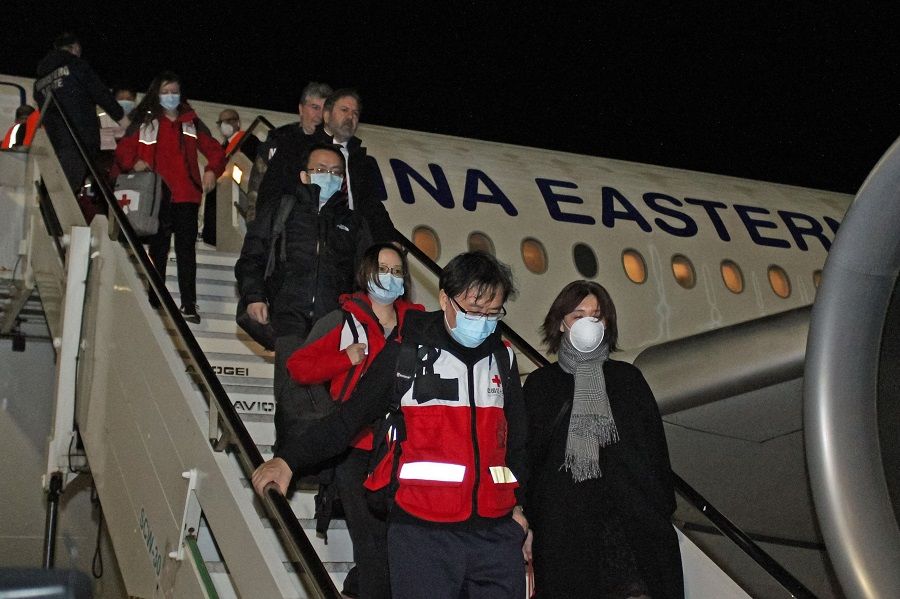 This photo provided by Italian news agency Ansa on 13 March 2020 shows Chinese medics going down a China Eastern flight after landing at Rome's Fiumicino international airport from Shanghai, bringing medical aid to help fight the new coronavirus in Italy. (STRINGER/ANSA/AFP)