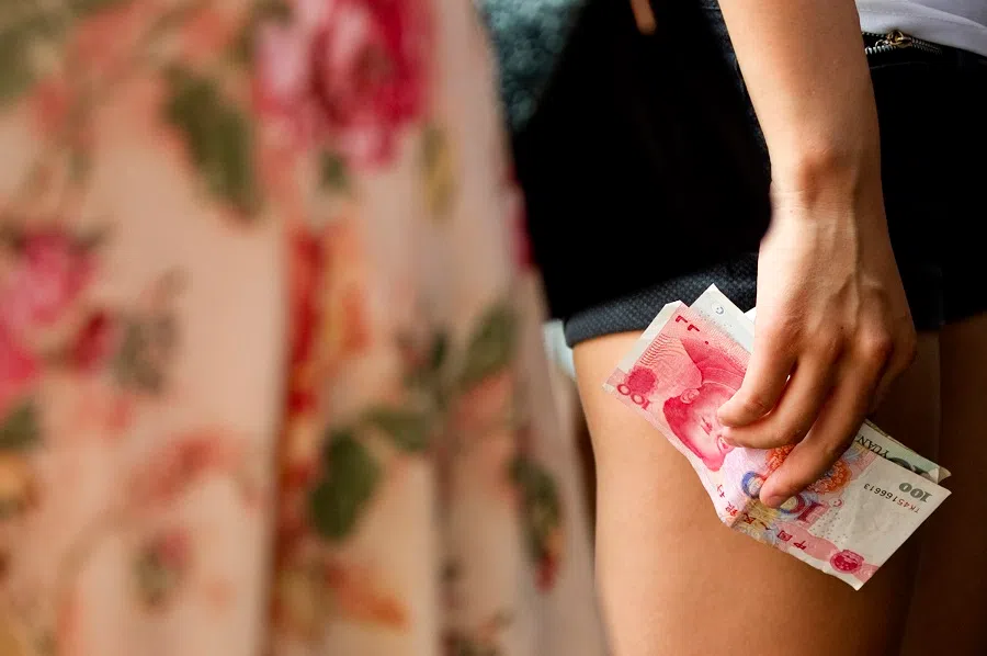 A tourist holds 100 RMB bank notes in Beijing, China, on 11 August 2011. (Stefen Chow/Bloomberg)