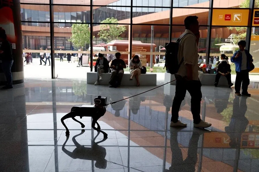 A man walks with a robot dog at the Beijing International Automotive Exhibition (Auto China), in Beijing, China, 24 April 2026. (Tingshu Wang/Reuters)
