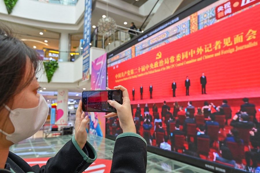A woman takes photos on a live broadcast of the introduction of the Chinese Communist Party's Politburo Standing Committee, on a screen at a shopping mall in Qingzhou in China's eastern Shandong province on 23 October 2022. (AFP)