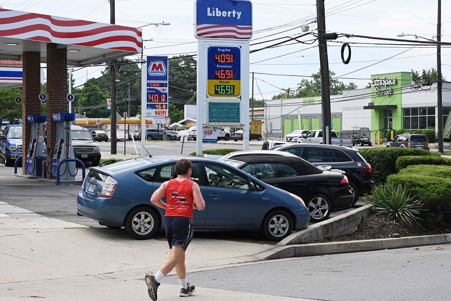 In this file photo taken on 11 August 2022, a jogger runs past gas stations in Bethesda, Maryland, US. (Mandel Ngan/AFP)
