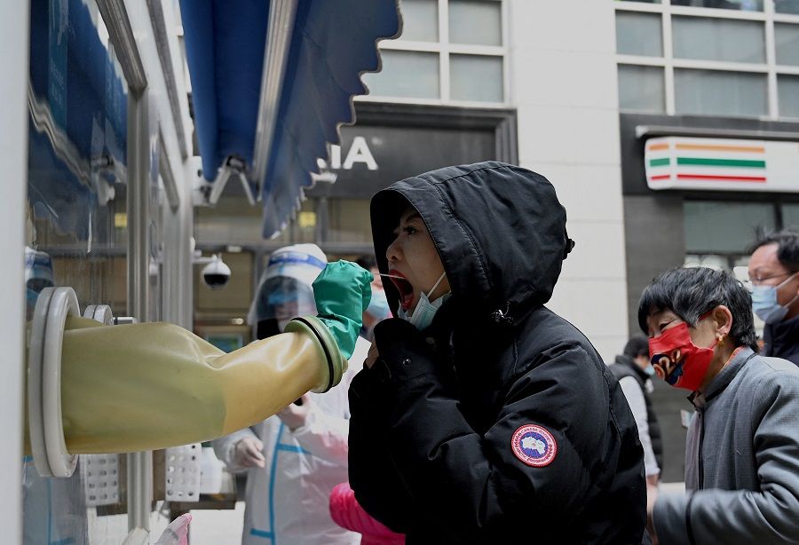 A health worker takes a swab sample from a woman to be tested for Covid-19 at a testing site in Beijing, China, on 19 January 2022. (Noel Celis/AFP)