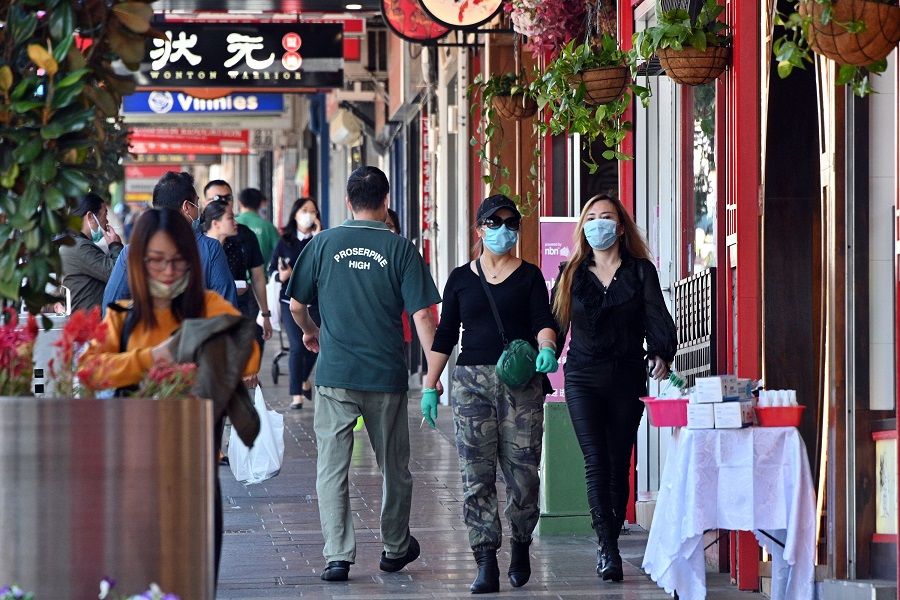 People wearing face masks walk in the Burwood suburb of Sydney on 14 April 2020, amid the Covid-19 pandemic. (Saeed Khan/AFP)