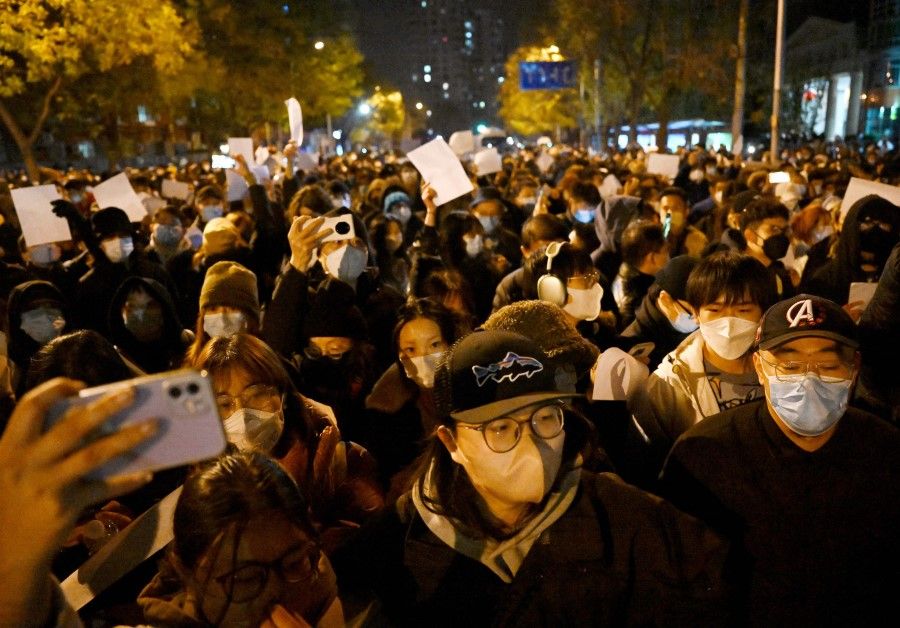 Protesters march along a street during a rally for the victims of a deadly fire as well as a protest against China's harsh Covid-19 restrictions in Beijing on 28 November 2022. (Noel Celis/AFP)