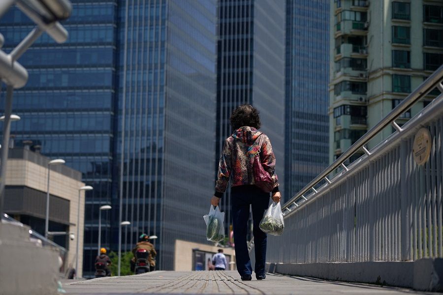 A woman walks on a bridge in Shanghai, China, 9 May 2023. (Aly Song/Reuters)