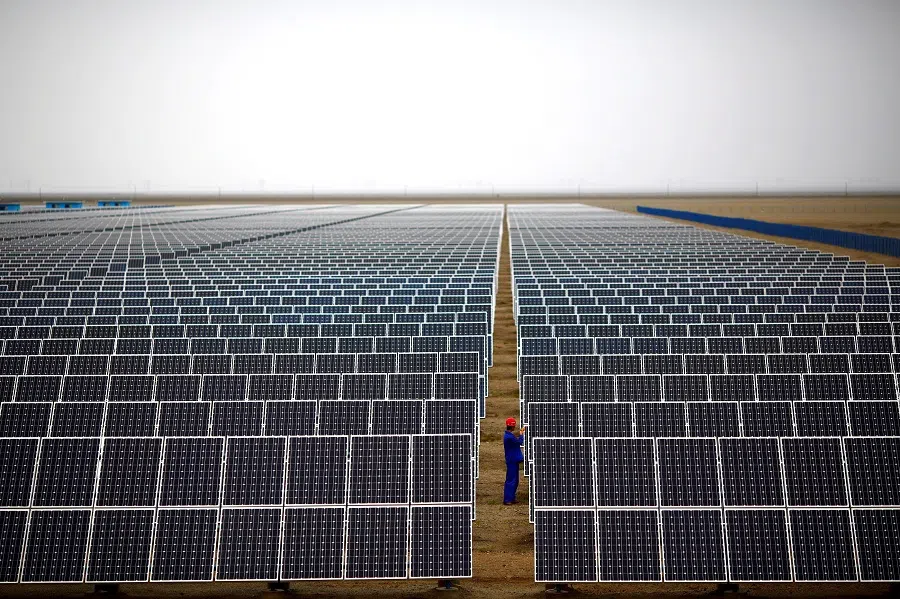 A worker inspects solar panels at a solar farm in Dunhuang, 950 km northwest of Lanzhou, Gansu province, on 16 September 2013. (Carlos Barria/Reuters)