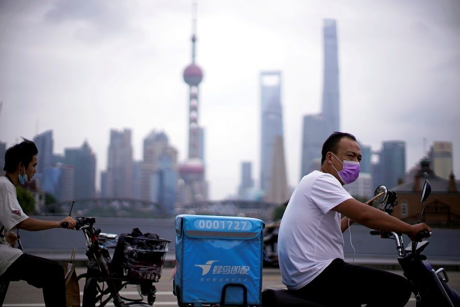 Delivery workers wearing face masks ride scooters in front of Lujiazui financial district, in Shanghai, China, 10 July 2020. (Aly Song/File Photo/Reuters)
