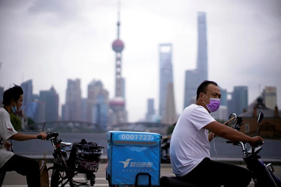 Delivery workers wearing face masks ride scooters in front of Lujiazui financial district, in Shanghai, China, 10 July 2020. (Aly Song/File Photo/Reuters)