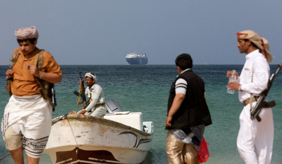 Armed men stand on the beach as the Galaxy Leader commercial ship, seized by Yemen's Houthis last month, is anchored off the coast of Al-Salif, Yemen, on 5 December 2023. (Khaled Abdullah/Reuters)
