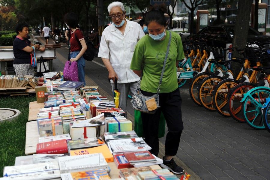 People look at books displayed at a street stall at the Sanlitun shopping area in Beijing, 5 June 2020. (Tingshu Wang/REUTERS)