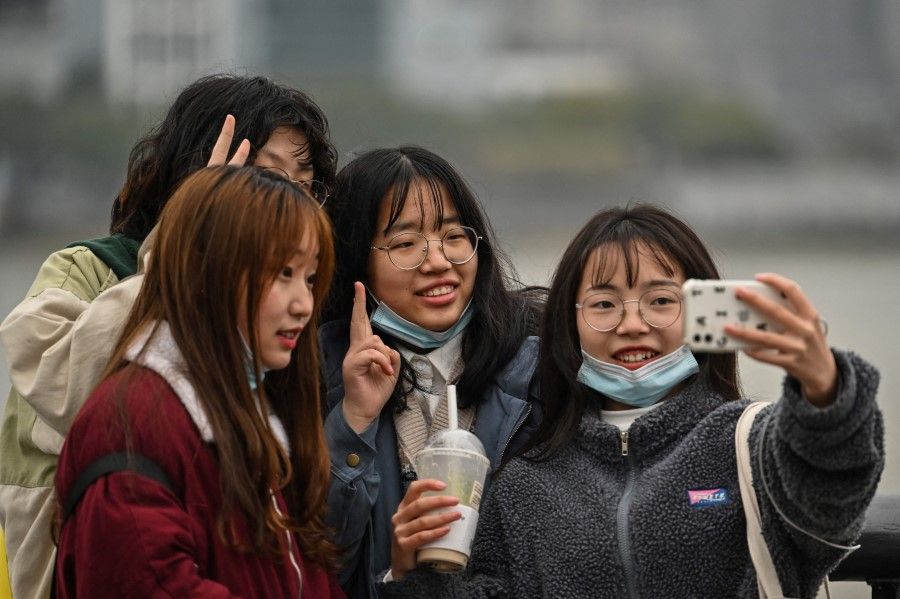 Women pose for a picture on the Bund promenade along the Huangpu River in Shanghai on 7 March 2021. (Hector Retamal/ AFP)