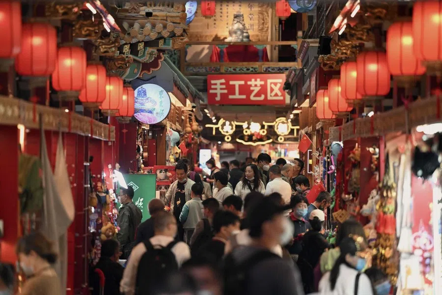 People walk at an alley in Qianmen street during the second day of the National Day holiday in Beijing on 2 October 2022. (Noel Celis/AFP)