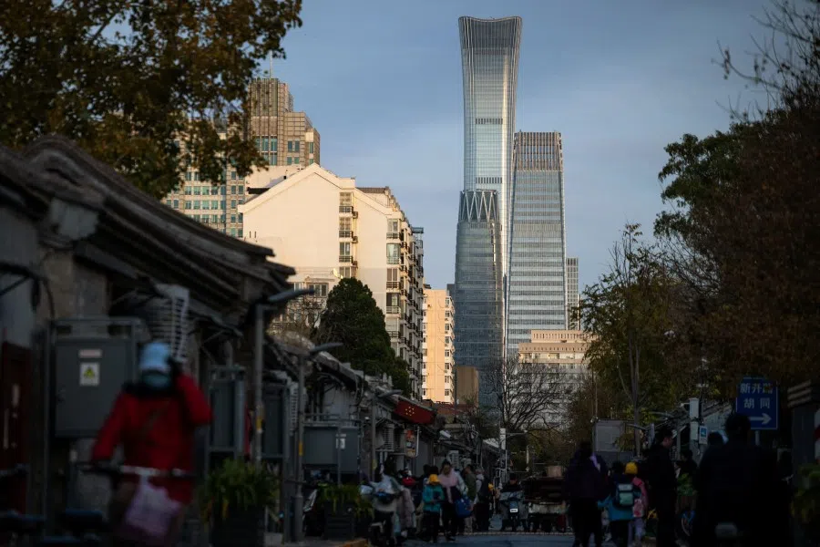 People walk in the street in a hutong area with a view on skyscrapers of central business district (CBD) in the background during sunset in Beijing, China,on 12  November 2025. (Maxim Shemetov/Reuters)