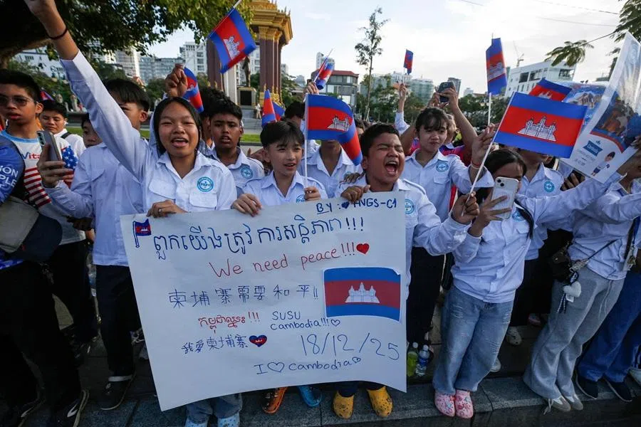 People hold a banner and wave Cambodian flags as they take part in a march to support Cambodia and to call for peace in the Cambodia-Thailand border conflict, in Phnom Penh on 18 December 2025.