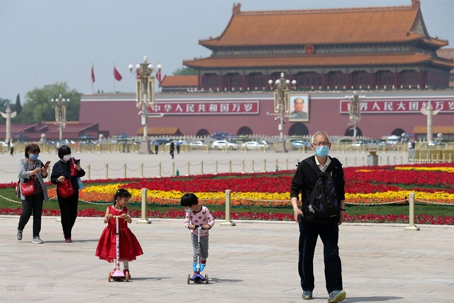 People wearing face masks following the Covid-19 coronavirus outbreak walk past flower installations set up to mark the upcoming Labour Day holiday, at Tiananmen Square in Beijing, China on 29 April 2020. (China Daily via Reuters)