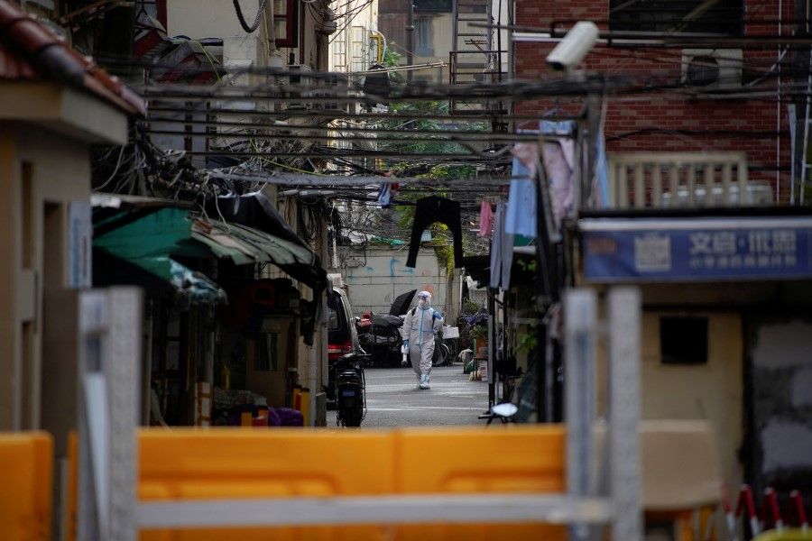 A worker in a protective suit disinfects at a closed residential area during lockdown, amid the Covid-19 pandemic, in Shanghai, China, 17 May 2022. (Aly Song/Reuters)