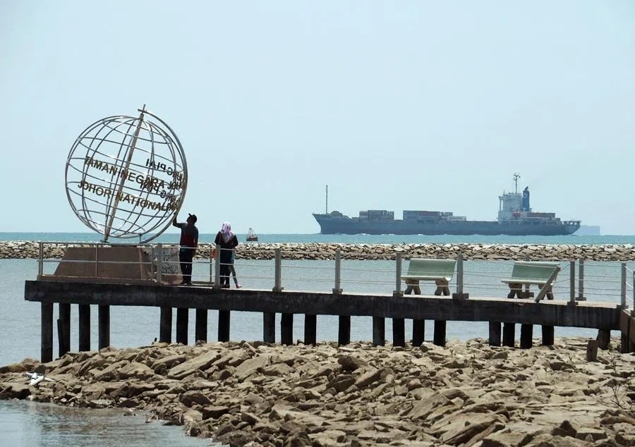 A container ship enters the Singapore Strait for the Strait of Malacca, as tourists stand at mainland Asia's southern most point in Johor, Malaysia, 12 November 2016. (Henning Gloystein/Reuters)