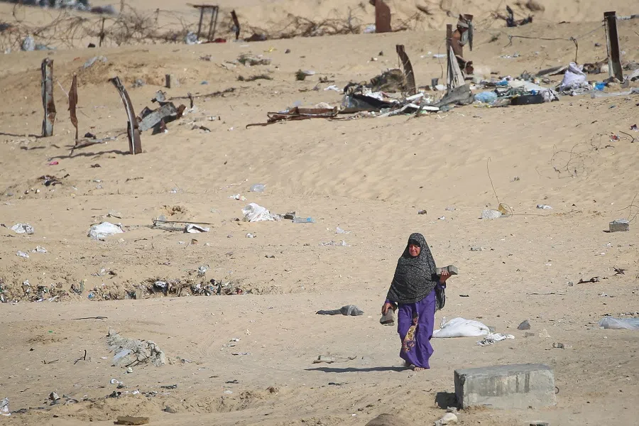 A displaced Palestinian woman walks away from a dismantled camp in Rafah as people moved to safer areas in central Gaza on 15 May 2024, while Israeli forces continued to battle and bomb the southern Gaza Strip city. (AFP)