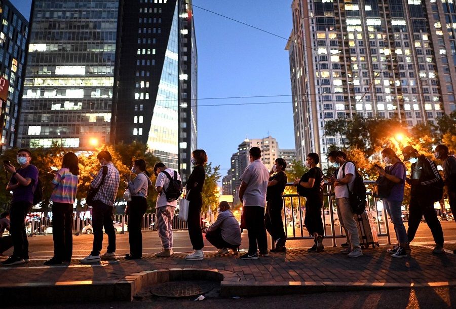 People queue at a bus stop during evening rush hour in Beijing, China, on 27 August 2021. (Noel Celis/AFP)
