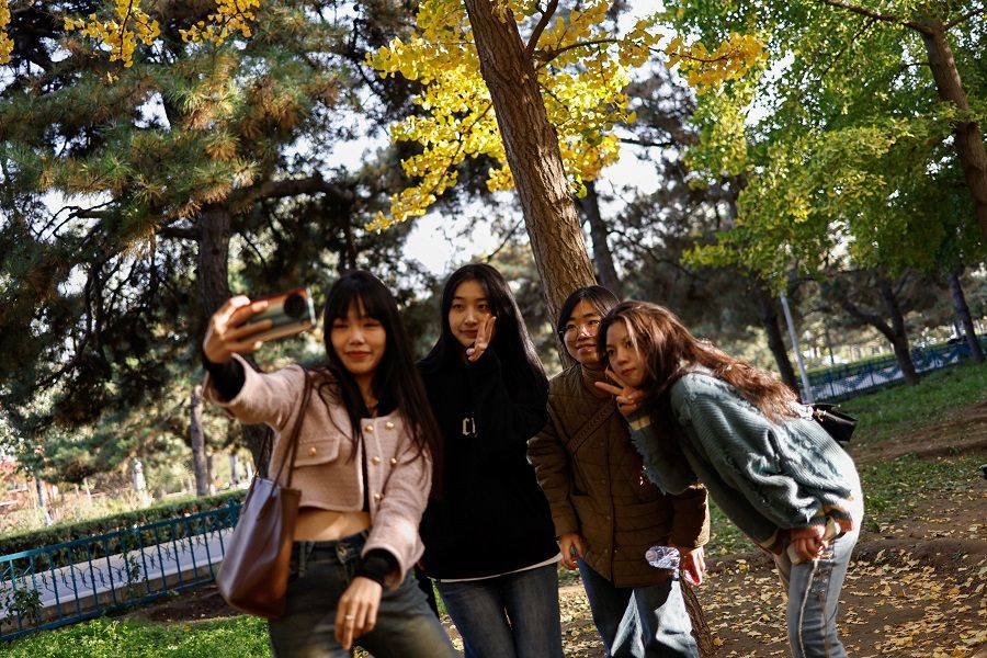 People take selfies under ginkgo trees on an autumn day in Beijing, China, on 3 November 2023. (Tingshu Wang/Reuters)