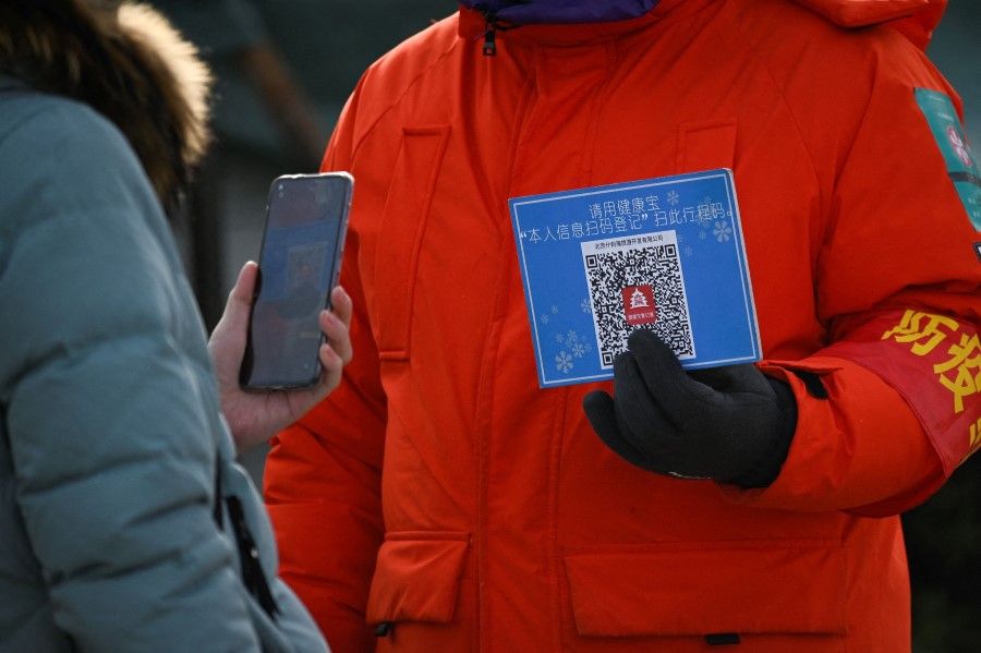 This file photo taken on 12 January 2021 shows a woman using her mobile phone to scan a QR code for health registration before entering an outdoor ice rink in Beijing. (Wang Zhao/AFP)