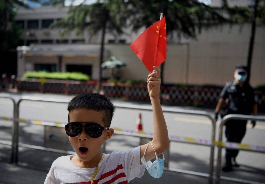 A boy waves a Chinese flag in front of the US consulate in Chengdu, southwestern China's Sichuan province, 26 July 2020. (Noel Celis/AFP)