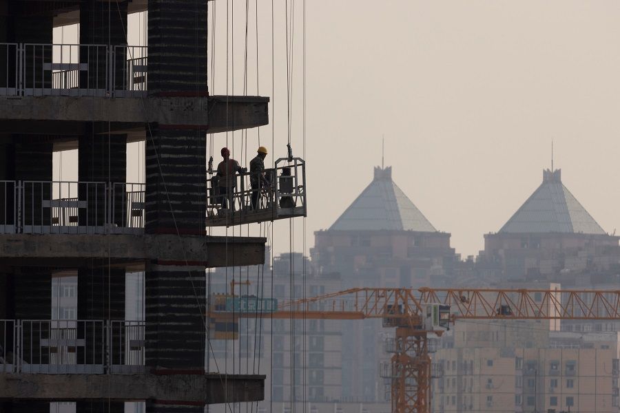 Men work at the construction site of a high-rise building in Beijing, China, 18 October 2021. (Thomas Peter/Reuters)