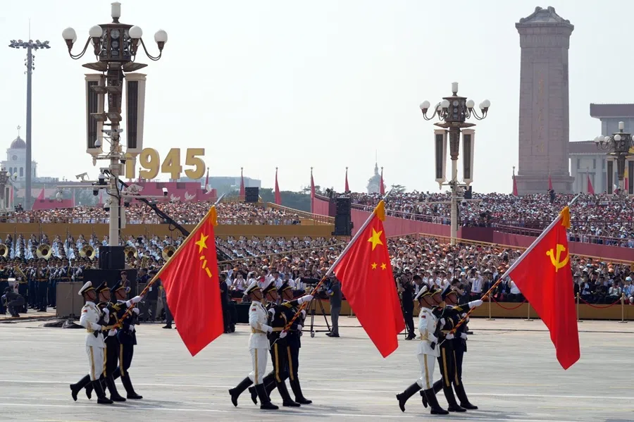 Members of the People’s Liberation Army (PLA) carry the flags of the Chinese Communist Party, right, China, centre, and PLA on Chang’an Avenue at Tiananmen Square during a military parade to mark 80 years since Japan’s defeat in World War II held in Beijing, China, on 3 September 2025. (Qilai Shen/Bloomberg)