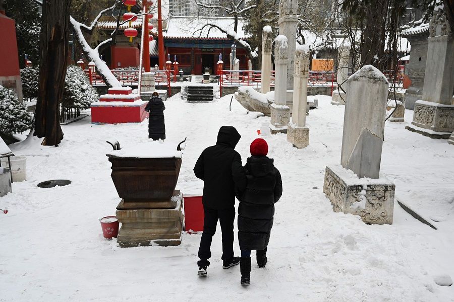 A couple walks through a temple during a snowfall in Beijing on 14 December 2023. (Greg Baker/AFP)