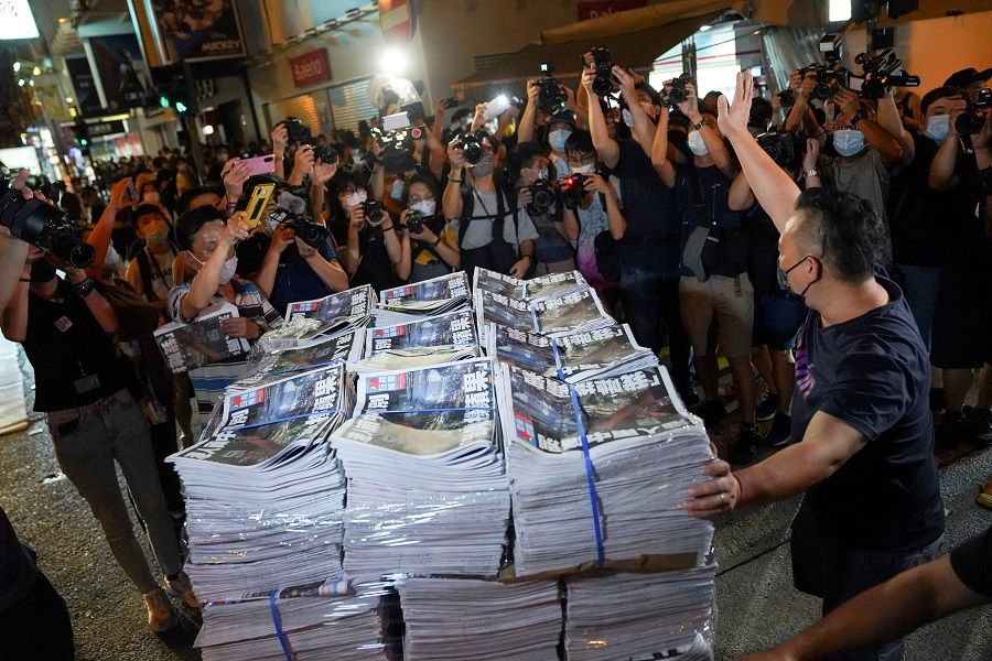 A man gestures as he brings copies of the final edition of Apple Daily, published by Next Digital, to a news stand in Hong Kong, China, 24 June 2021. (Lam Yik/File Photo/Reuters)