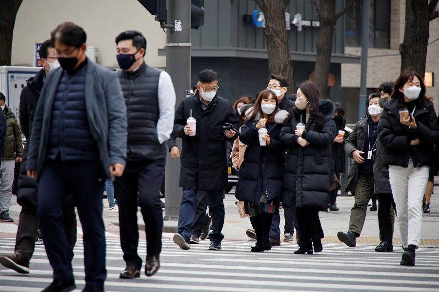 People wearing masks walk on a zebra crossing in Seoul, South Korea, 5 January 2022. (Heo Ran/Reuters)