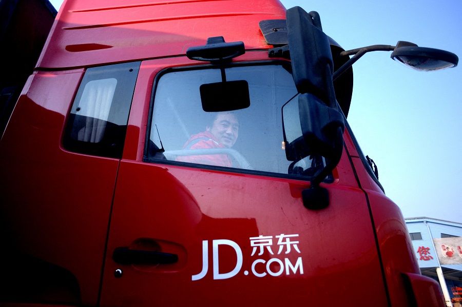 This file photo taken on 3 November 2015 shows a driver for online marketplace JD.com smiling as he sits in his truck outside the company's warehouse in Langfang, Hebei province, China. (Wang Zhao/AFP)