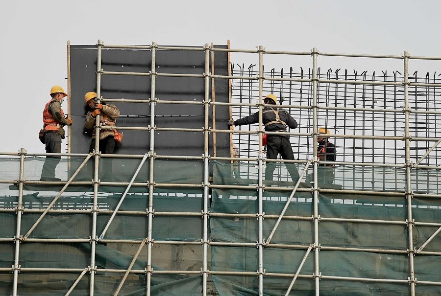 Workers move materials on scaffolding at a construction site in Beijing, China, on 8 December 2021. (Noel Celis/AFP)